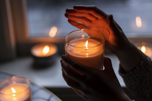 Hands holding lit candle illustrating relaxation and aromatherapy for de-stressing.