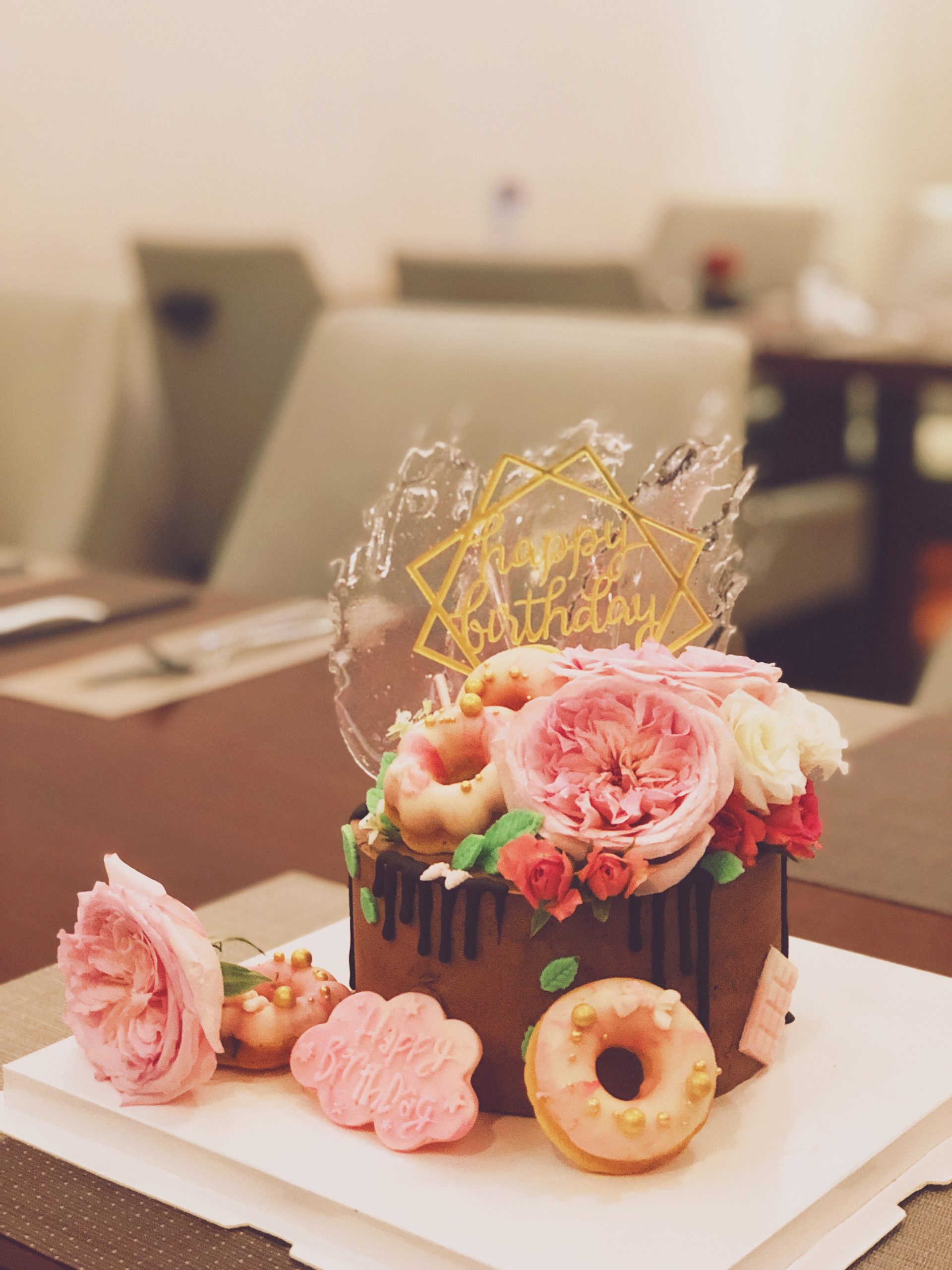 Birthday cake and floral arrangement with "Happy Birthday" decorations, representing self-care during quarantine.