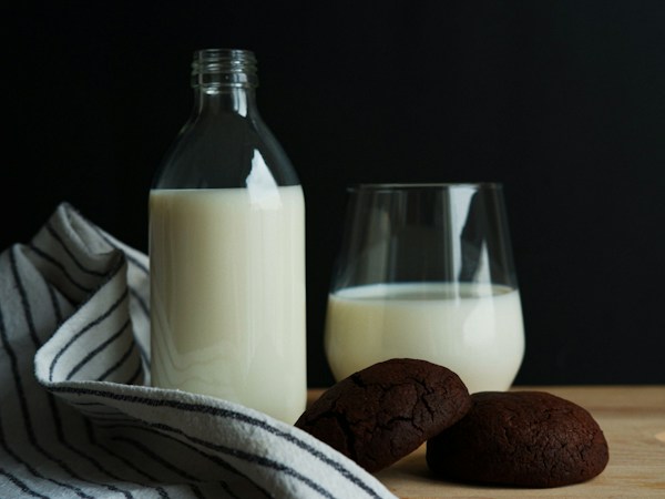 Dairy-free milk in glass bottle and drinking glass with chocolate cookies