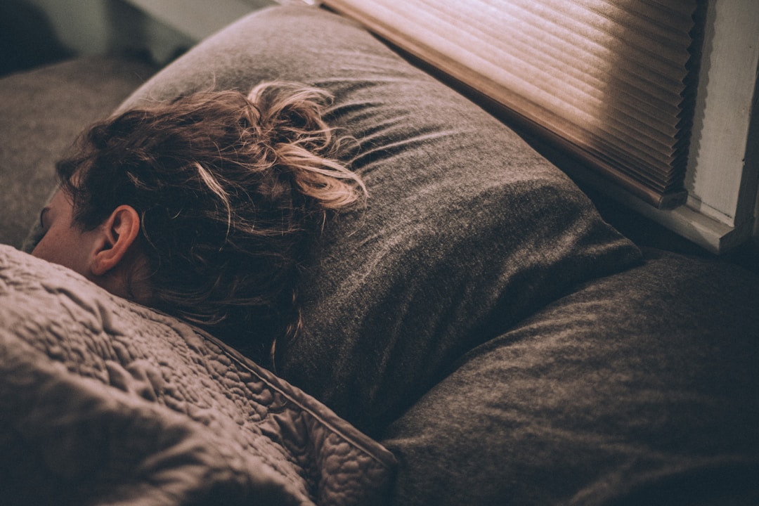 Person resting head on pillow illustrating the importance of sleep and wellness.