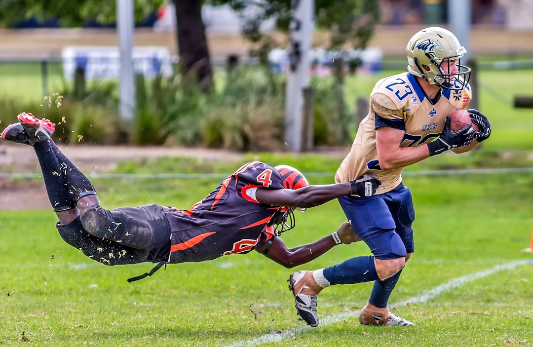 High school football player running with ball, defender attempting tackle, illustrating game strategy and player positioning.