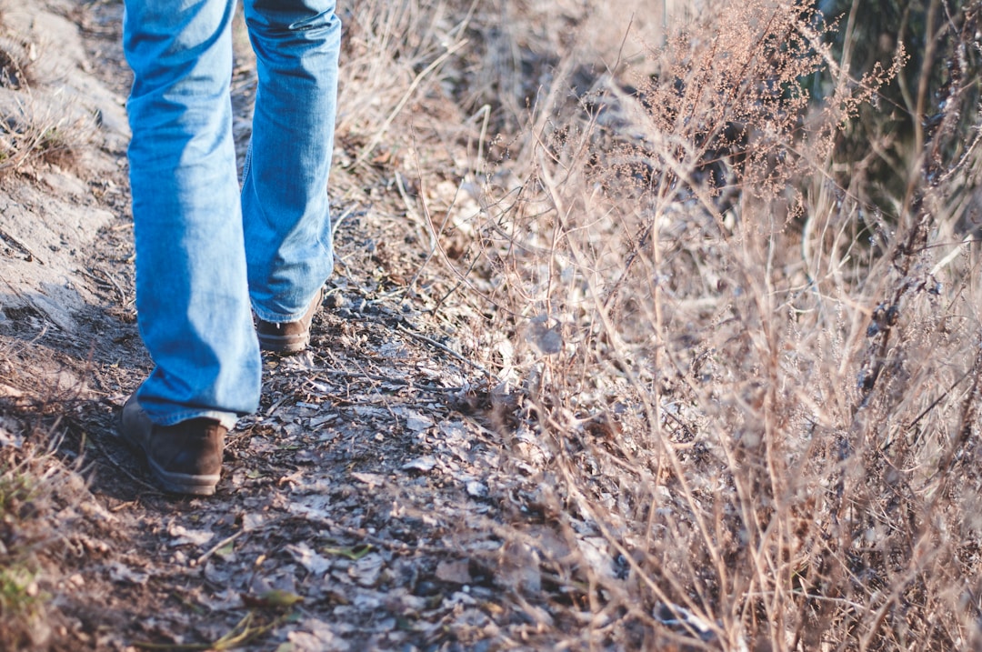 Person walking in jeans and shoes on a natural path, illustrating foot comfort and pain relief.