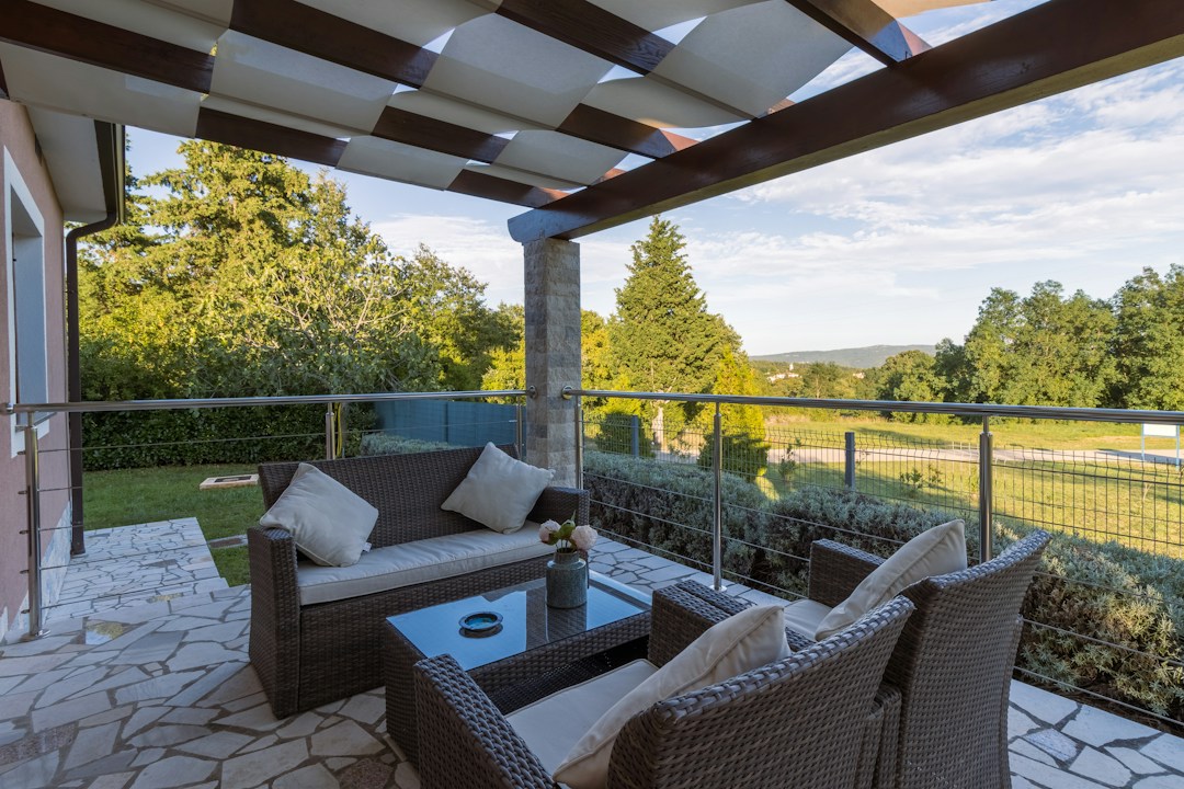 Outdoor seating area with cable railing and pergola, enhancing view of landscape.