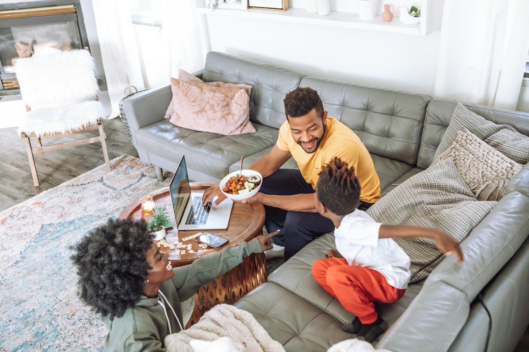 Family relaxing at home with laptop and covered appliances.