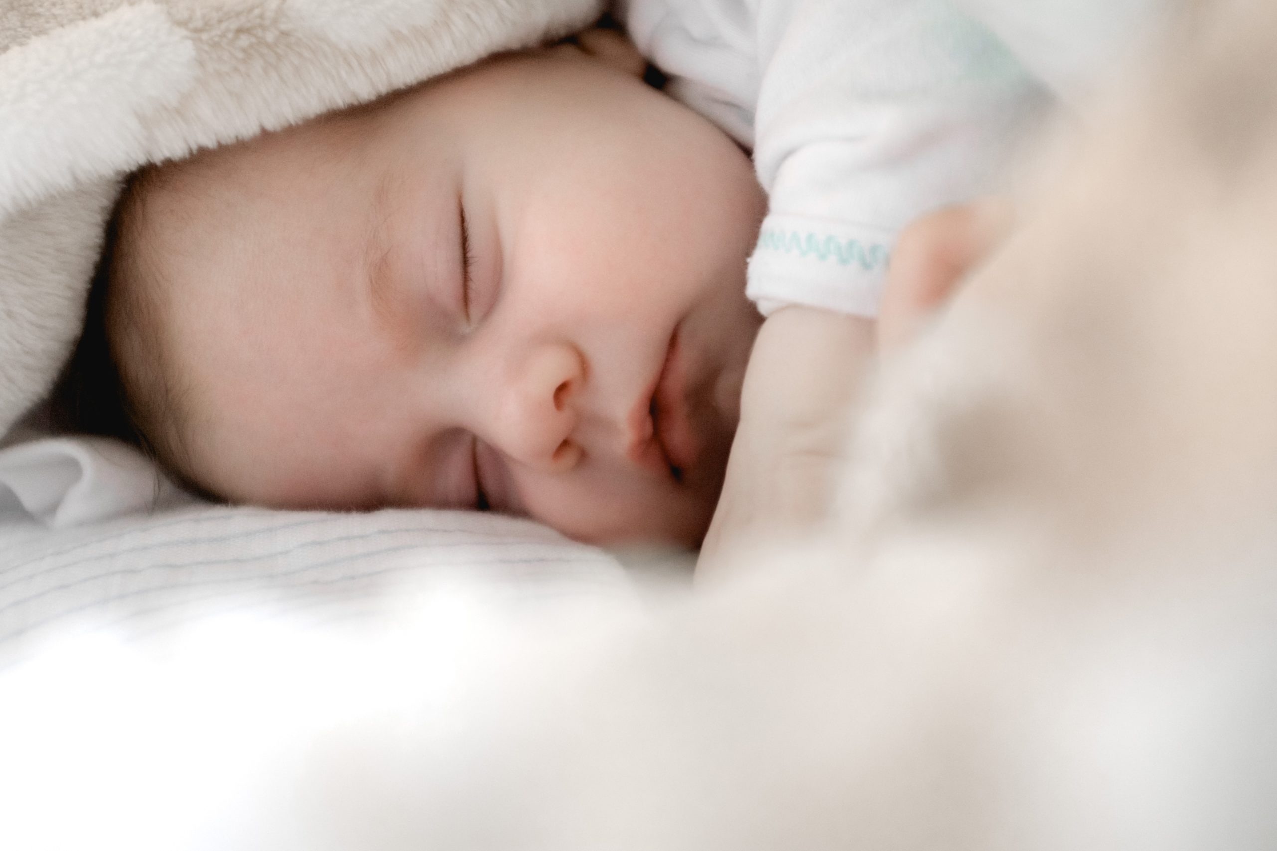 Sleeping baby wrapped in a soft blanket, representing new life and family planning.