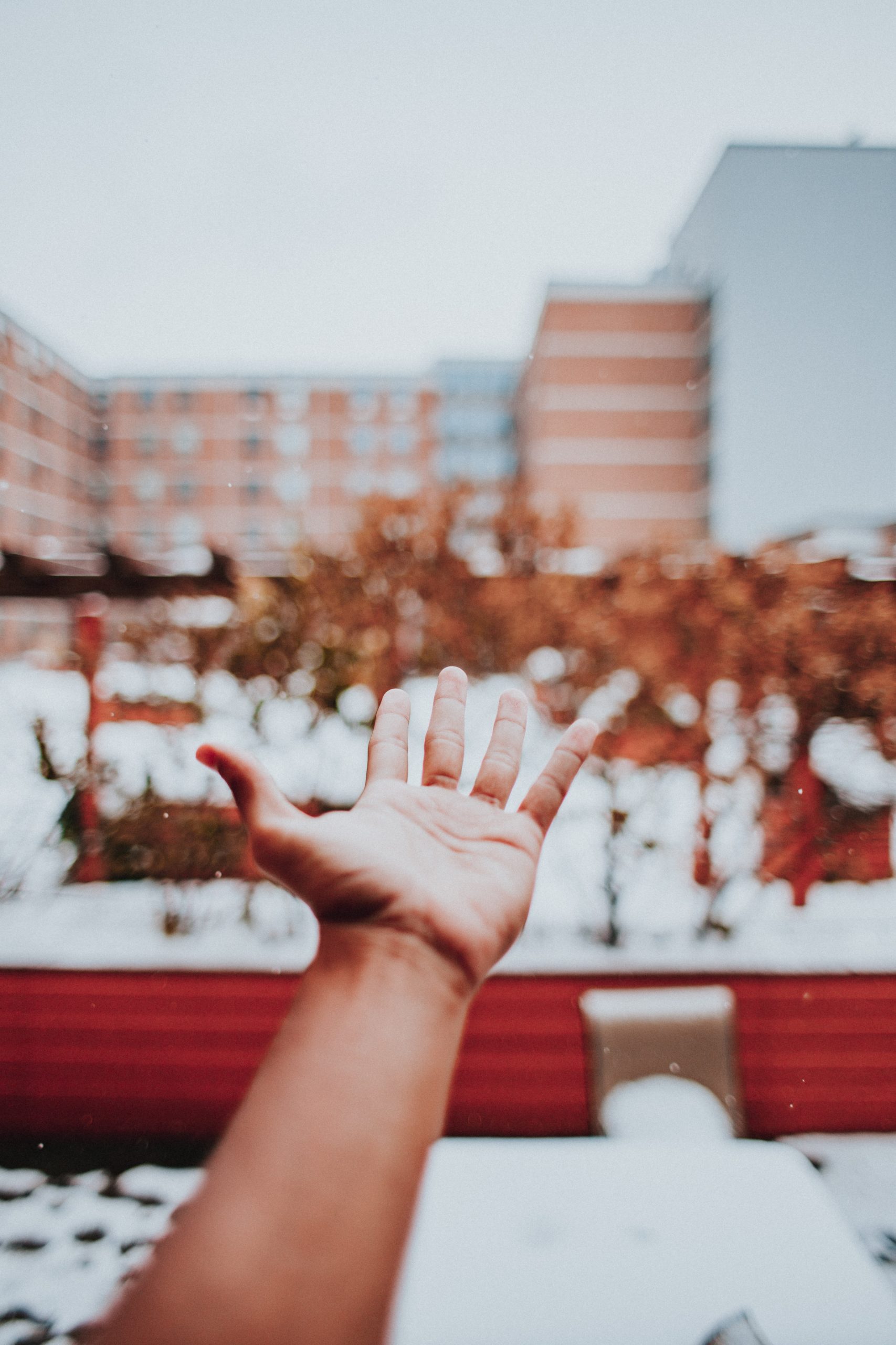 Hand reaching out in a snowy urban landscape, representing selfcare and overcoming bad habits.