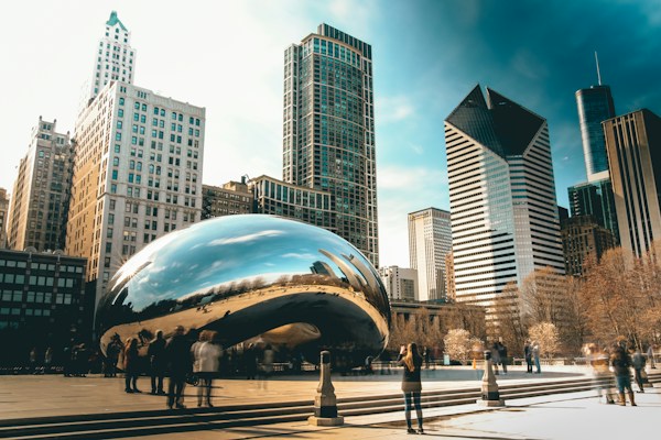 Chicago skyline and Cloud Gate reflecting city buildings and people.