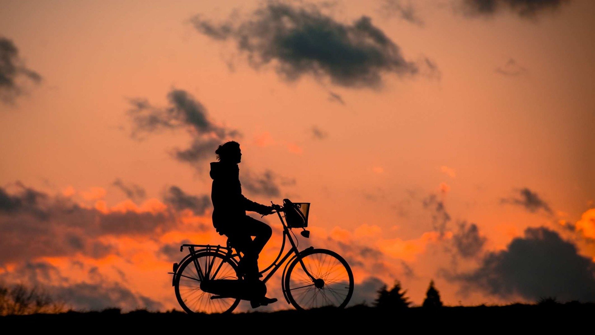 Silhouette of person cycling at sunset, promoting physical well-being and a balanced lifestyle.