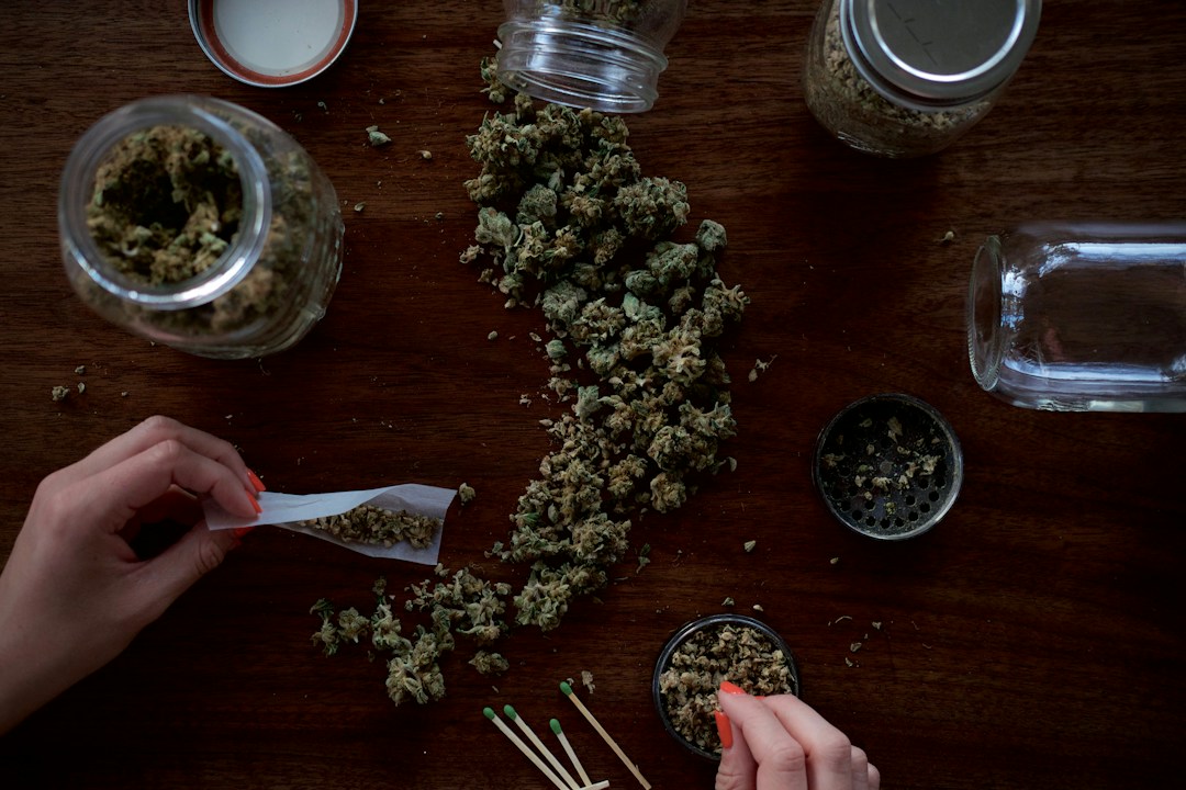 Cannabis buds and rolling papers on wooden surface illustrating first-time smoker preparation.