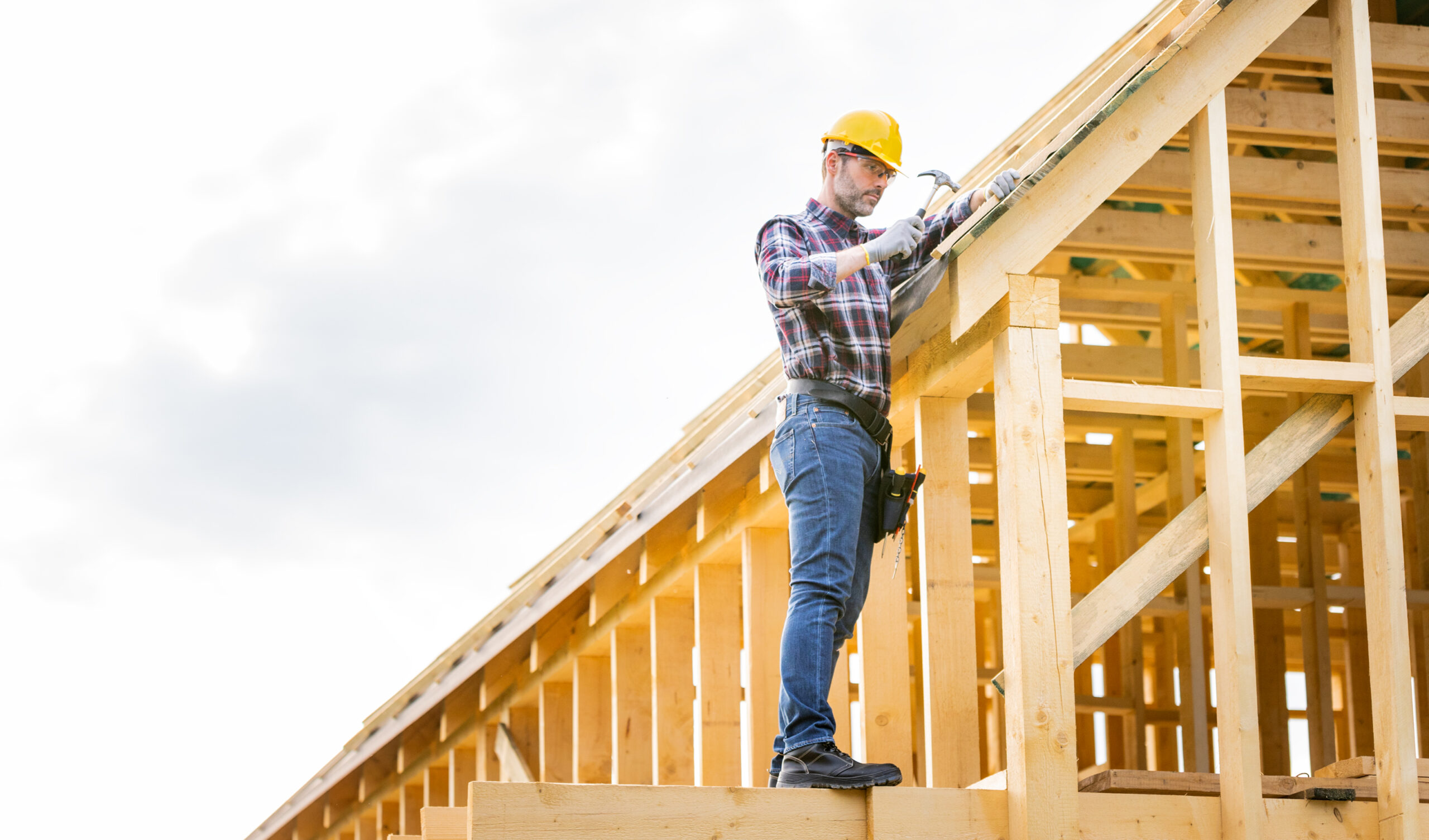 Roofer working on roof structure at construction site, replacing roof in Massachusetts