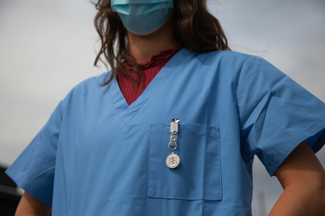 Healthcare professional in blue scrubs and badge, travel healthcare career, professional development.