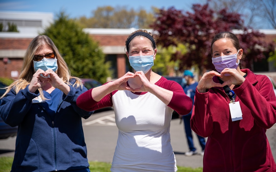 Healthcare professionals forming heart shapes with their hands in front of a hospital, travel healthcare careers.