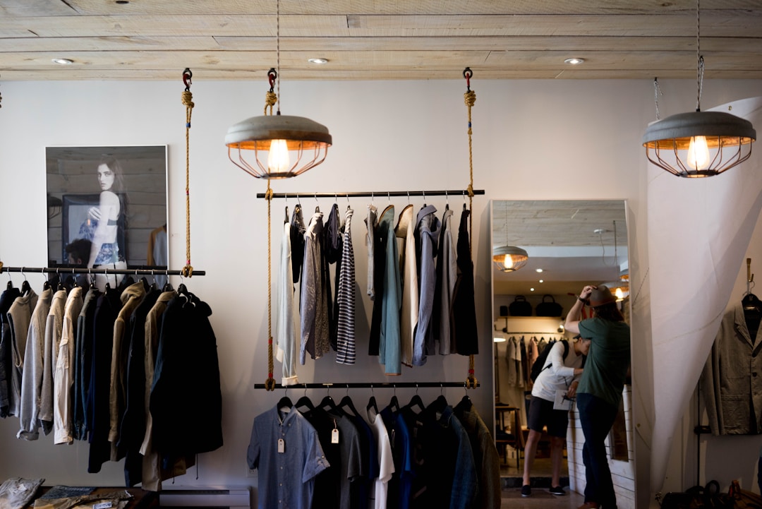 Stylish clothing racks and pendant lighting in a thrift store setting.