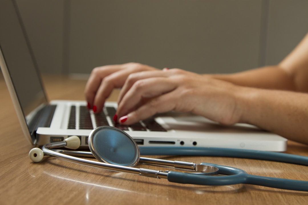 Healthcare professional working on laptop and stethoscope, illustrating travel healthcare career.