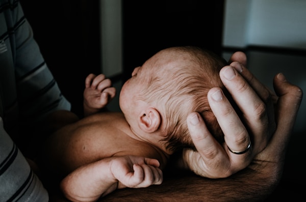 Parent gently supporting newborn baby's head and neck.