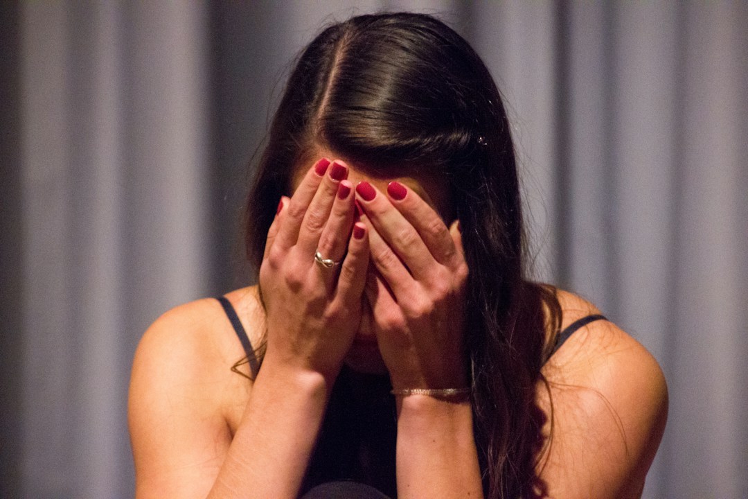 Woman covering face expressing distress and trauma symptoms.
