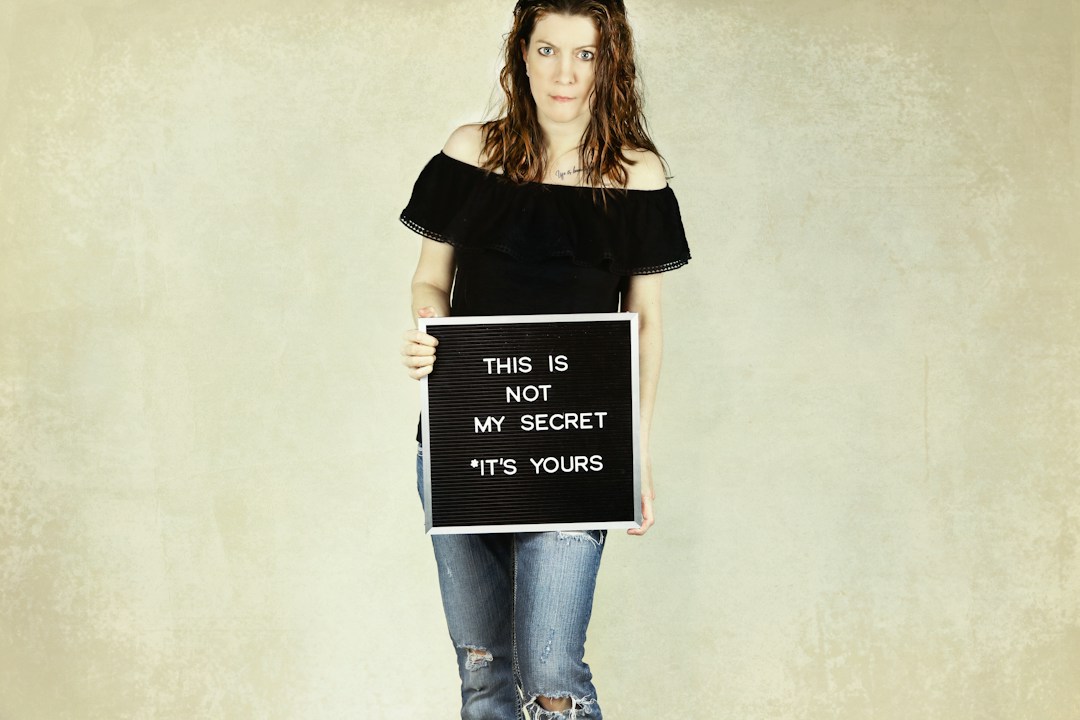 Woman holding sign with message about sharing secrets and social advocacy.