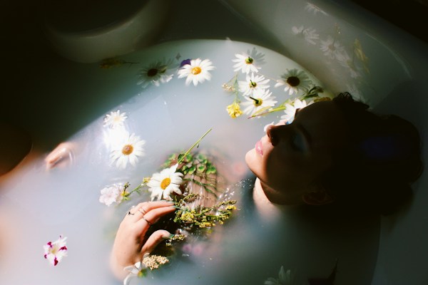 Woman relaxing in a warm bath with flowers, promoting relaxation and wellbeing.