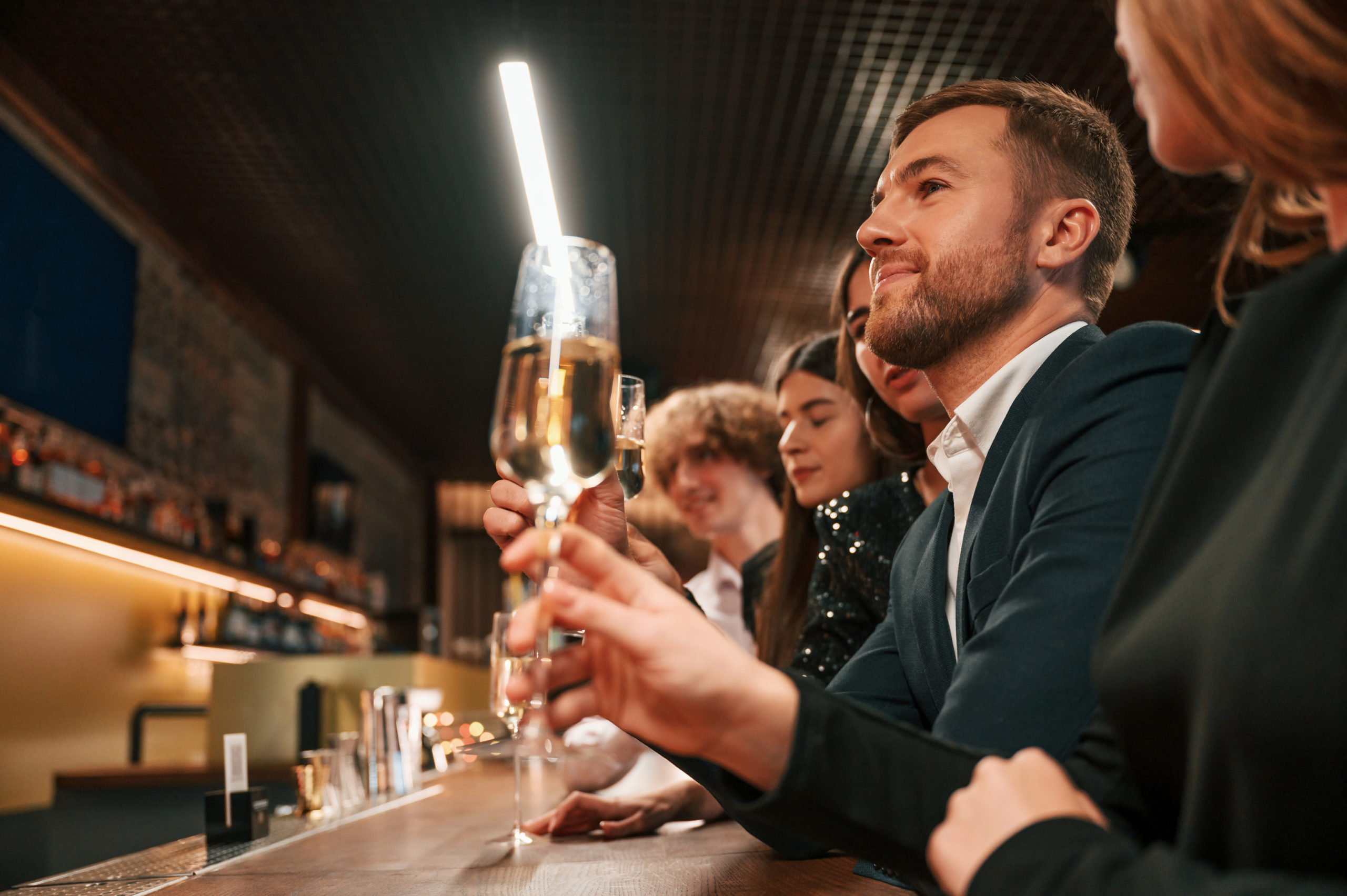 Group of people celebrating New Year indoors, toasting with champagne glasses.