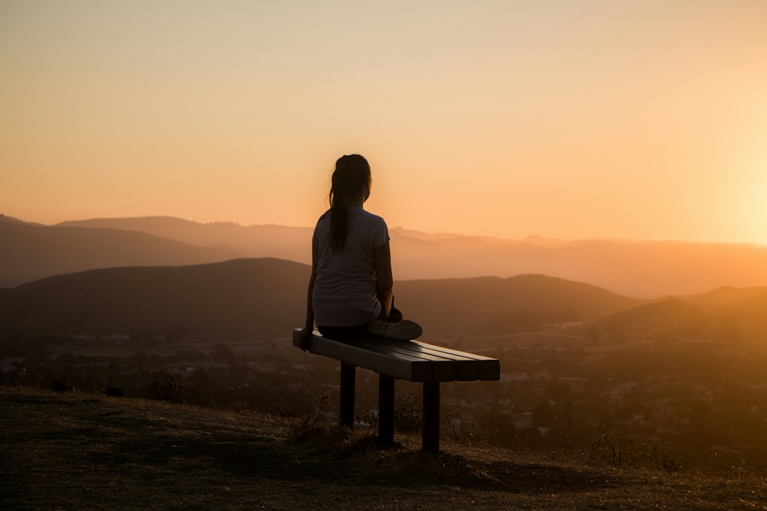 Person meditating at sunset for relaxation and mental wellness.