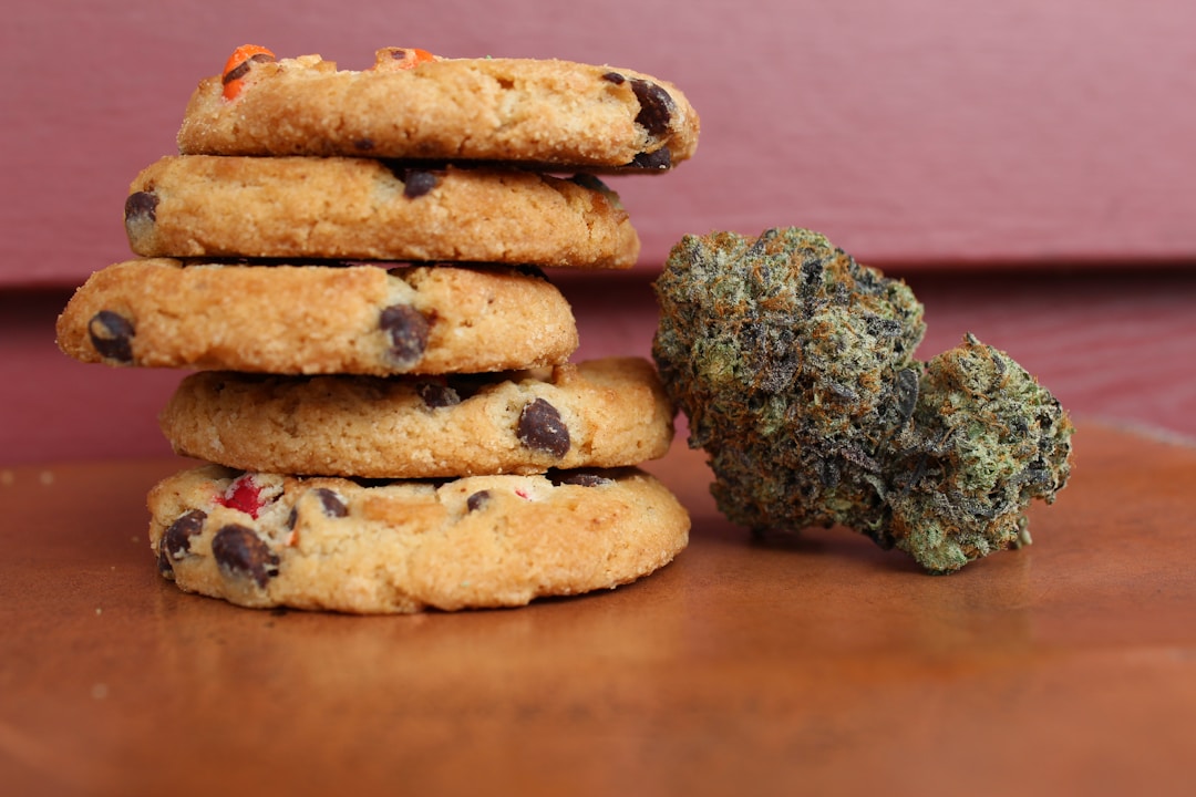 Stack of chocolate chip cookies and cannabis buds illustrating marijuana products and edible consumption.