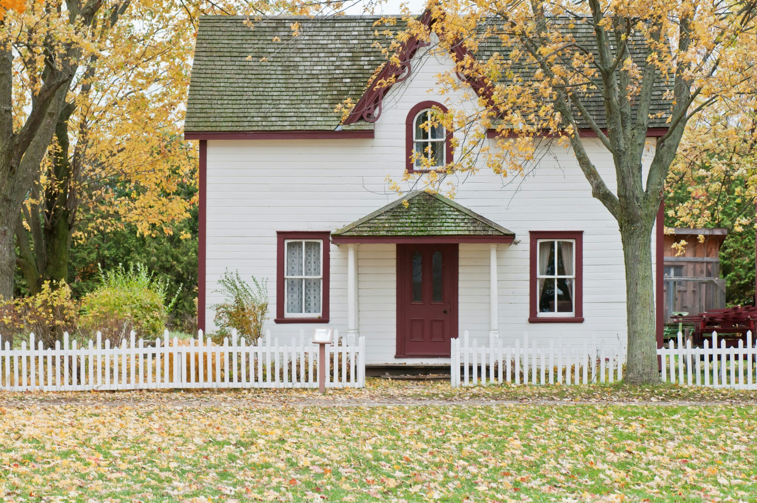 Ready-to-move home exterior with white picket fence and autumn foliage.