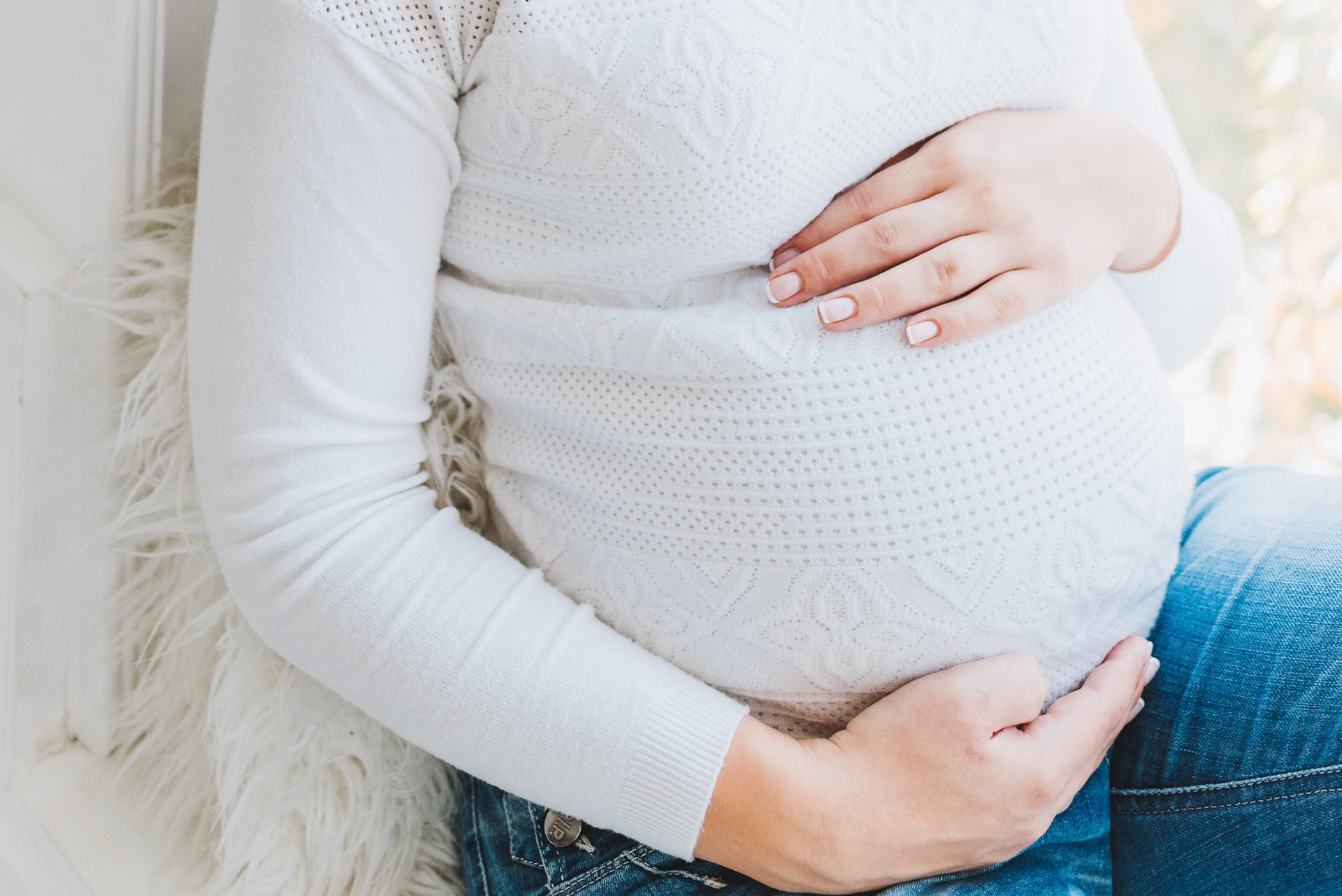 Expecting mother gently touching pregnant belly, illustrating pregnancy and childbirth.